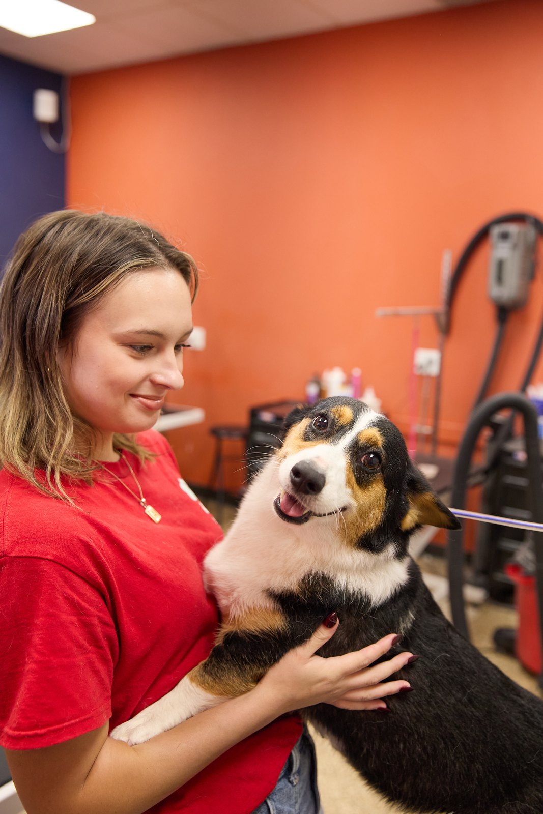 A Happy K9 groomer cuddling a tri-color dog after a groom